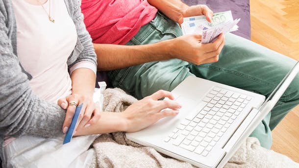 Mand og kvinde sidder med penge og en computer
