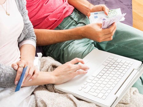 Mand og kvinde sidder med penge og en computer