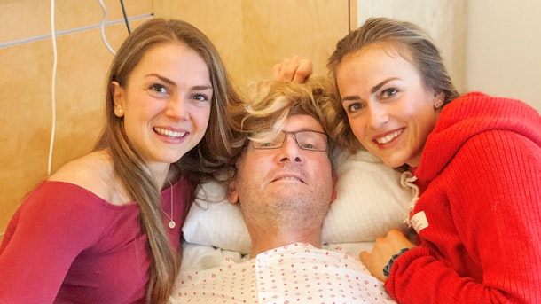 To døtre ligger i fars arme i hospitalsseng