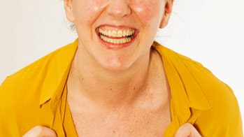 Kvinde står med gul bluse og smiler