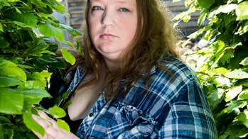 Overvægtig dame står mellem to grønne buske