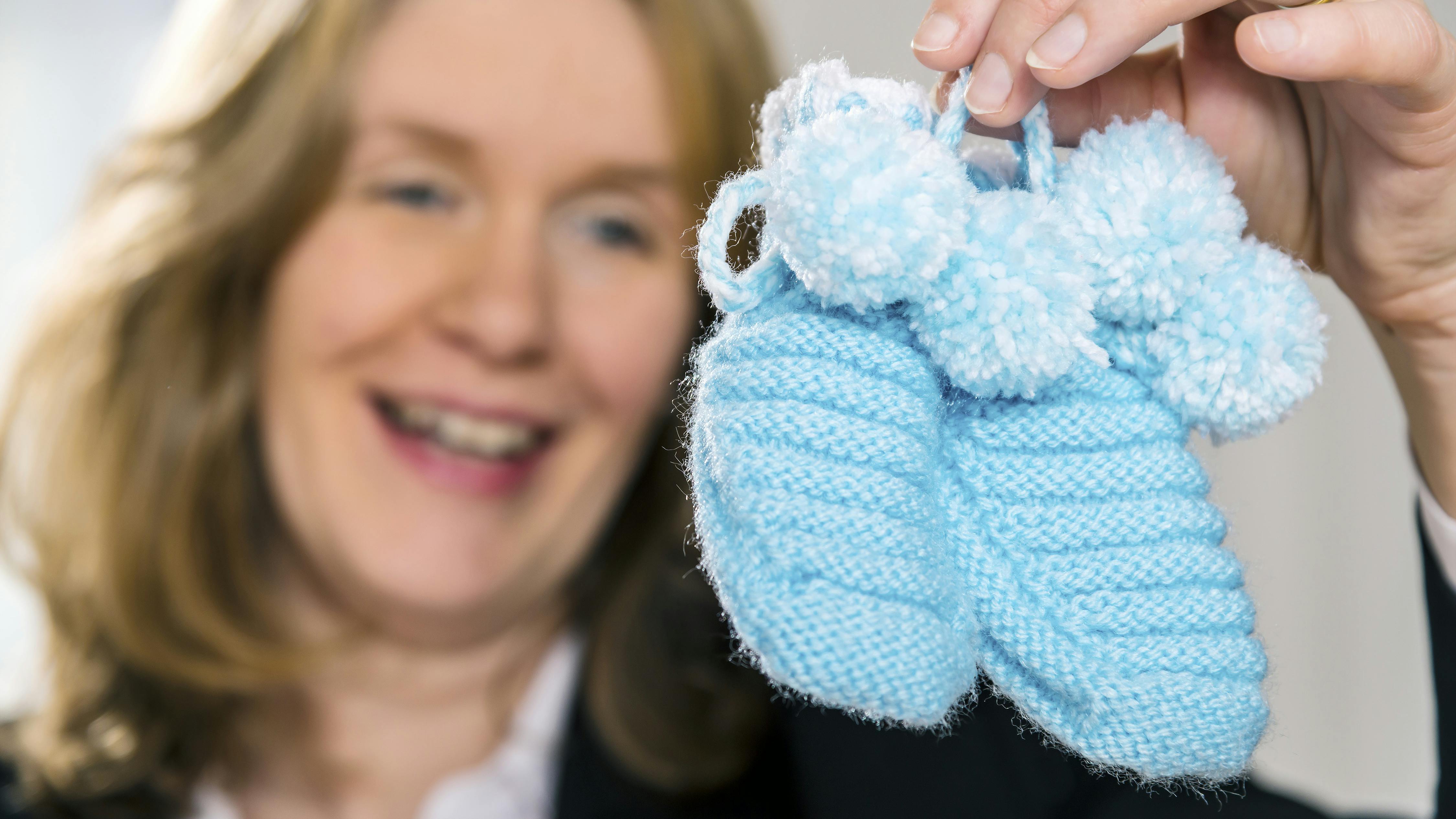 Kvinde kigger på babytøj. Hun er skruk