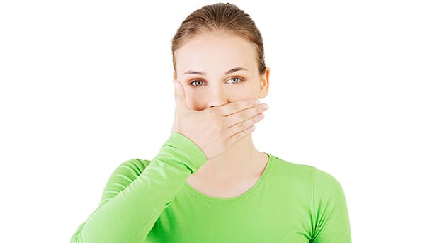 Kvinde lider af sure opstød og holder sig for munden 