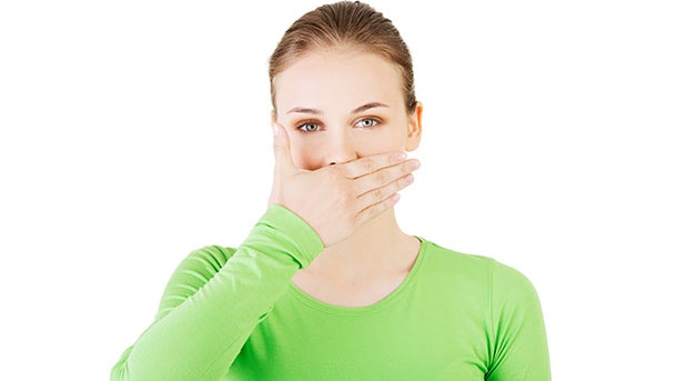 Kvinde lider af sure opstød og holder sig for munden 