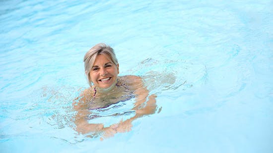 Svømning: Glad kvinde der svømmer i pool  