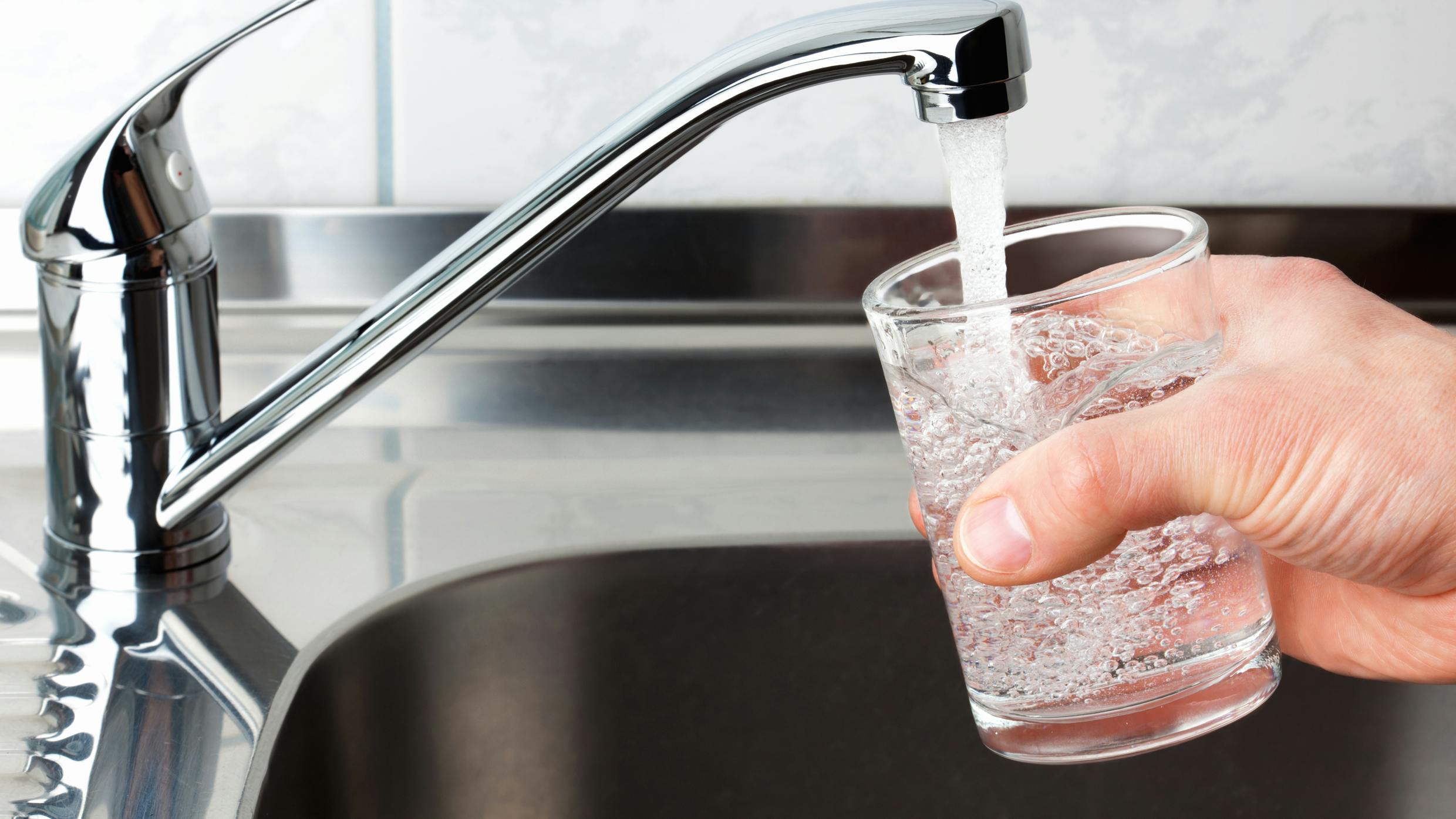 Der tappes vand fra vandhanen ned i et glas. lithium i drikkevandet beskytter mod demens