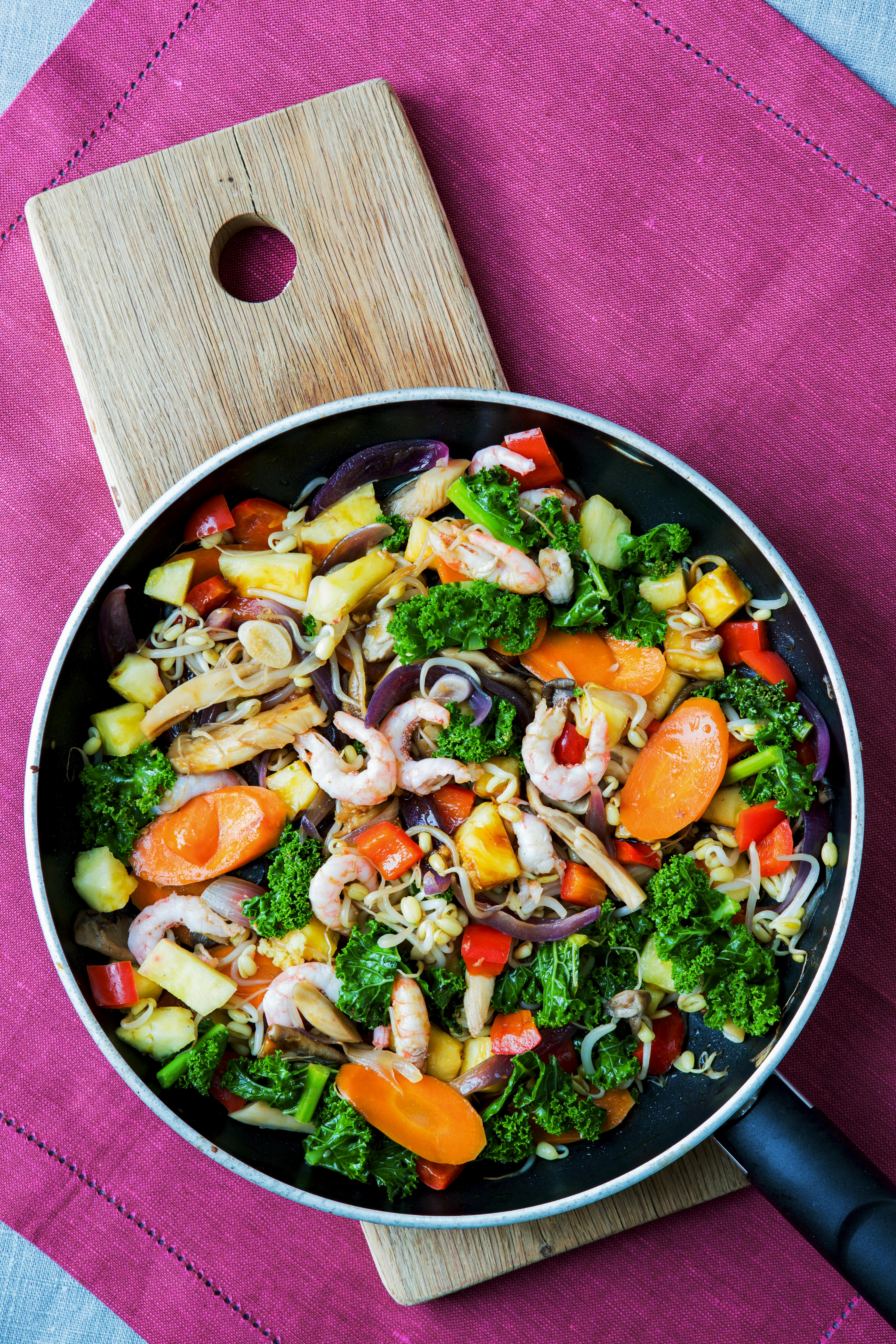 Indbydende ret tilberedt i wok med masser af grøntsager, rejer og ananas