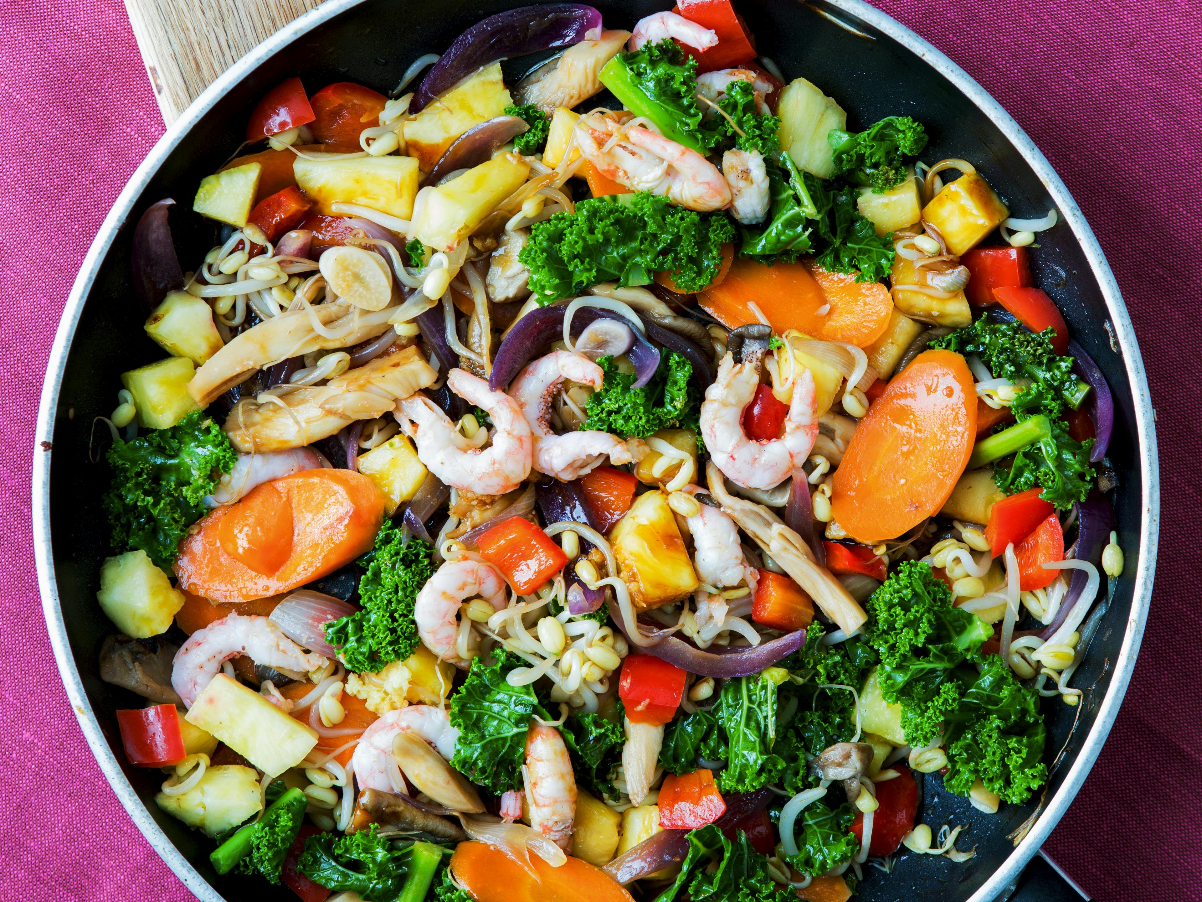 Indbydende ret tilberedt i wok med masser af grøntsager, rejer og ananas
