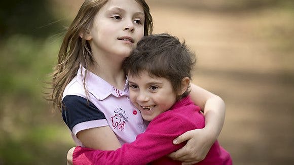 Seksårige Milly krammer sin storesøster, der er stolt over at  have givet sin lillesøster et helt nyt liv.
