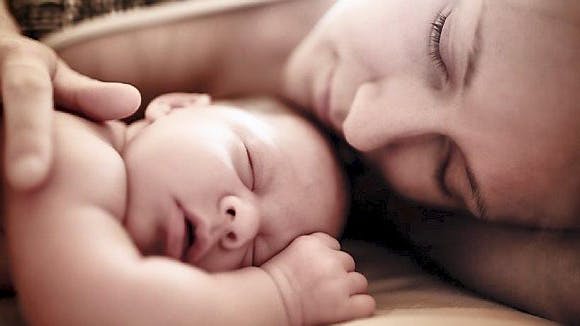 Børn: Kvinde der sover med sin baby